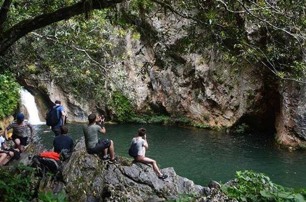 Tourists take photos of the Caburni Waterfall, in Topes de Collantes, Trinida de Cuba