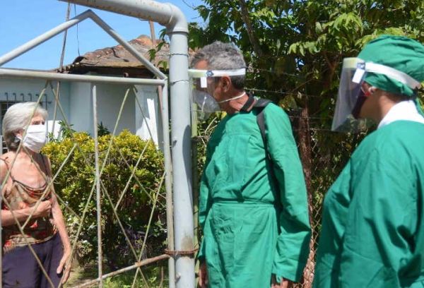 Two health workers stand outside a house to do the corresponding daily survey