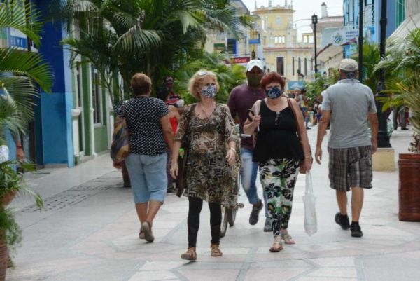 People walking along the Boulevard Street of Sancti Spiritus, all of them wearing face masks