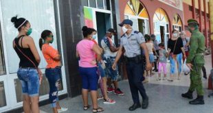 police officers watch the discipline of people who are standing in line outside a cafeteria in sancti spiritus, cuba